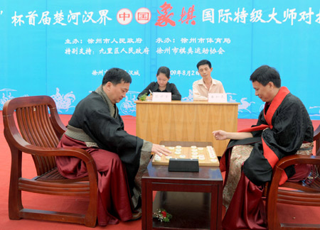 International grandmasters of Chinese chess Lu Qin (1st R) and Xu Tianhong (1st L) play chess in Xuzhou of Jiangsu Province, east of China, Aug. 2, 2009. Actors performing as chessmen simulated the game at the same time. Lu won the game. (Xinhua/Li Ming)