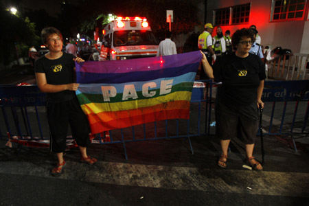 Israelis hold a gay pride flag near the scene of a shooting incident in a basement club in central Tel Aviv Aug. 2, 2009.[Xinhua/Reuters]