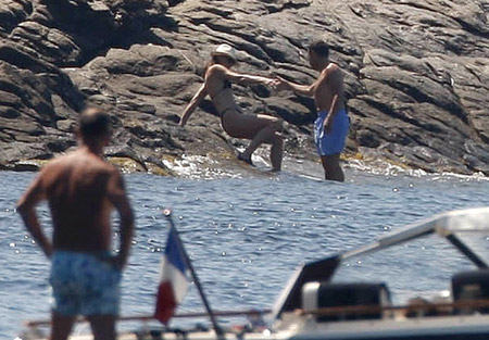 France's President Nicolas Sarkozy (R) and his wife Carla Bruni-Sarkozy descend rocks into the Mediterranean Sea below the villa belonging to the family of France's first lady which is perched on the secluded promontory of Cap Negre, near Cavaliere, August 1, 2009. [Xinhua/Reuters]