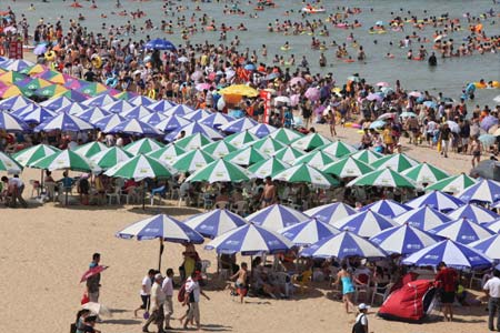 Thousands of people flock to a bathing beach to cool themselves in Lianyungang, east China's Jiangsu Province, Aug. 1, 2009.[Wang Jianmin/Xinhua]