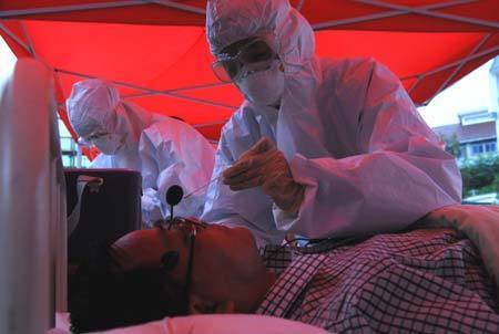 Chinese medics inspect a 'patient' of influenza A/H1N1 during a drill for the flu prevention in Xiuning County of Huangshan, in east China's Anhui Province, Aug.2, 2009.[Liu Bingsheng/Xinhua]