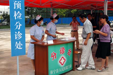 Chinese medics receive a 'patient' of influenza A/H1N1 during a drill for the flu prevention in Xiuning County of Huangshan, in east China's Anhui Province, Aug.2, 2009.[Liu Bingsheng/Xinhua]