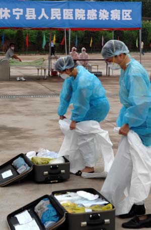 Chinese medics put on prevention uniforms for influenza A/H1N1 during a drill for the flu prevention in Xiuning County of Huangshan, in east China's Anhui Province, Aug.2, 2009.[Liu Bingsheng/Xinhua]