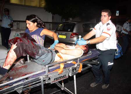 An Israeli paramedic rushes a wounded man to an ambulance after a shooting incident in a basement club in central Tel Aviv Aug. 1, 2009. A shooting incident happened in a Tel Aviv club Saturday night, causing three dead and at least 10 wounded, local media reported. [Xinhua/Reuters]