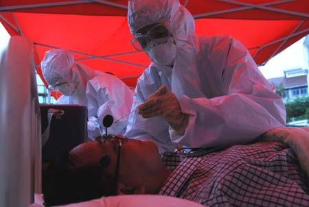 Chinese medics inspect a 'patient' of influenza A/H1N1 during a drill for the flu prevention in Xiuning County of Huangshan, in east China's Anhui Province, Aug.2, 2009.[Xinhua]