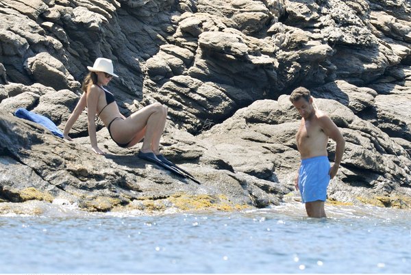 France's President Nicolas Sarkozy (R) and his wife Carla Bruni-Sarkozy descend rocks into the Mediterranean Sea below the villa belonging to the family of France's first lady which is perched on the secluded promontory of Cap Negre, near Cavaliere, August 1, 2009. [CFP]