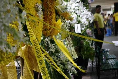 Floral bouquets are laid at the entrance to the hall where the remains of late Philippine President Corazon Aquino is placed at La Salle school gym in suburban Mandaluyong, east of Manila, Aug. 2, 2009. Corazon Aquino died early Saturday morning at 76 after battling colon cancer for over a year. [Luis Liwanag/Xinhua]