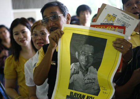 A Philippine man holds the portrait of assassinated Senator Benigno Aquino, husband of late Philippine President Corazon Aquino, at La Salle school gym, where the ramains of Corazon Aquino is placed, in suburban Mandaluyong, east of Manila, Aug. 2, 2009.[Luis Liwanag/Xinhua] 