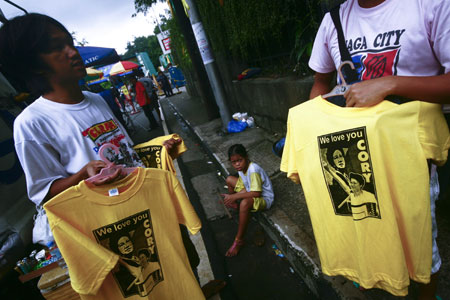 Philippine people sell shirts emblazoned with portraits of late Philippine President Corazon Aquino near La Salle school gym in suburban Mandaluyong, east of Manila, Aug. 2, 2009.[Luis Liwanag/Xinhua] 