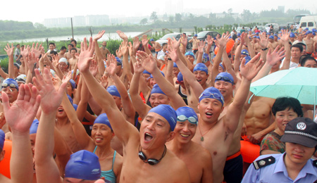 Swimmers cheer up for themselves before crossing over the Qiantang River in Hangzhou, capital of east China's Zhejiang Province, August 2, 2009. A total of 1300 swimmers took part in the activity of crossing over the Qiantang River on Sunday.Liang Yongfeng/Xinhua]