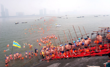 Swimmers take water and prepare to cross over the Qiantang River in Hangzhou, capital of east China's Zhejiang Province, August 2, 2009.[Liang Yongfeng/Xinhua]