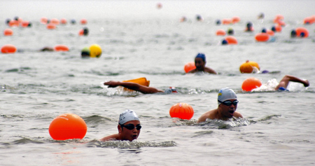 Swimmers cross over the Qiantang River in Hangzhou, capital of east China's Zhejiang Province, August 2, 2009.[Zhu Yinwei/Xinhua]