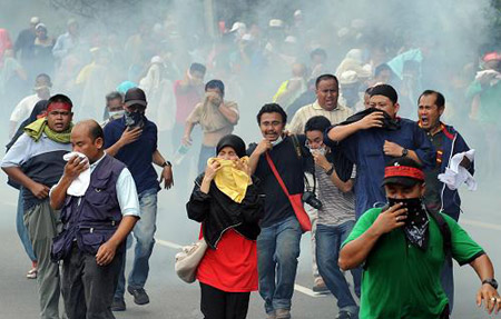 Demonstrators try to avoid the tear shells released by police in Kuala Lumpur, capital of Malaysia on August 1. More than 30,000 people took part in a massive demonstration against the Internal Security Act (ISA) in the city towards the National Palace to hand over a memorandum to the King on the abolishment of the ISA.[Xinhua/AFP]