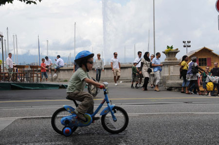 A boy rides a bicycle as he takes part in an activity named 'Slowup' alongside the Lake of Geneva in Geneva, Switzerland, Aug. 2, 2009. People could ride or walk on the 26-km-long road alongside the Lake of Geneva on Sunday, while the passage of motor vehicles was forbidden on the road. The activity aimed at improving the awareness of environment protection. [Yang Jingde/Xinhua]