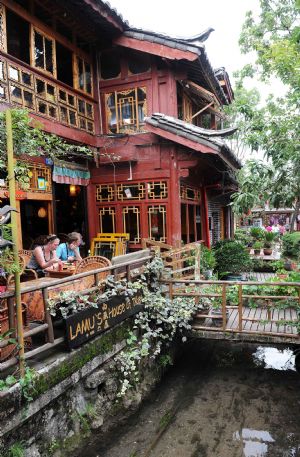 Two tourists have a meal in Lijiang, southwest China's Yunnan Province, on July 29, 2009. Lijiang received 3.44 million tourists in the first half of 2009, earning a tourism income of 3.88 billion RMB yuan (568 million U.S. dollars). Lijiang with an 800-year history was listed by the UNESCO in 1997 as a world cultural heritage site. (Xinhua/Lin Yiguang)