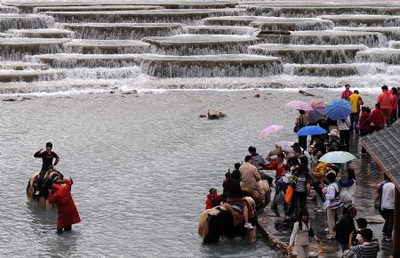 Tourists visit the Lanyuegu scenic area in Lijiang, southwest China's Yunnan Province, on July 28, 2009. Lijiang received 3.44 million tourists in the first half of 2009, earning a tourism income of 3.88 billion RMB yuan (568 million U.S. dollars). Lijiang with an 800-year history was listed by the UNESCO in 1997 as a world cultural heritage site. (Xinhua/Lin Yiguang)