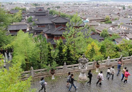 Tourists walk in Lijiang, southwest China's Yunnan Province, on July 27, 2009. Lijiang received 3.44 million tourists in the first half of 2009, earning a tourism income of 3.88 billion RMB yuan (568 million U.S. dollars). Lijiang with an 800-year history was listed by the UNESCO in 1997 as a world cultural heritage site. (Xinhua/Lin Yiguang)