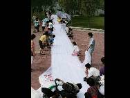 A view of the world's longest wedding dress train made by Zhao Peng to please his bride-to-be on August 1 in Jilin city of Jilin Province. It takes nearly three hours to unveil the train, which is 2,162 meters long and 1.5 meters wide. The train is set to break the existing world record of the longest wedding dress train, which measures 1579 meters. (China.org.cn / CFP)