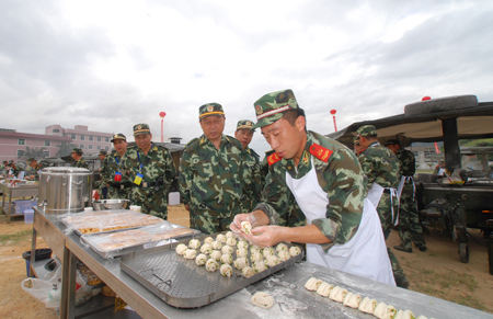 A Chinese armed policeman prepares food as he participates in a skill competition during a para-military logistic exercise in Fuzhou, capital of southeast China's Fujian Province, August 3, 2009.[Zeng Zhaoqun/Xinhua]