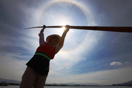 A woman of Bai ethnic group rows in the sun on West Lake, in Eryuan County, Dali Bai Autonomous Prefecture, southwest China's Yunnan Province, Aug. 3, 2009. Dali is the only autonomous prefecture of Bai ethnic group in China and has a population of 3,470,000 with one third of which from Bai.[Liu Yu/Xinhua]