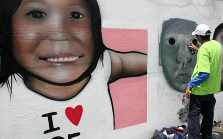 An graffiti artist paints on a 217-meter-long board near an art gallery in Mexico City, Aug. 2, 2009. [Xinhua]