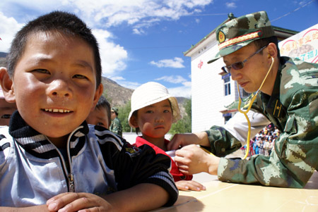 A surgeon gives check-up to children at Tibet Children's Welfare Home in Lhasa, capital of southwest China's Tibet Autonomous Region, August 1, 2009. A group of armed policemen paid a visit to Tibet Children's Welfare Home on Saturday and brought children living and learning articles. [Liang Jianming/Xinhua]