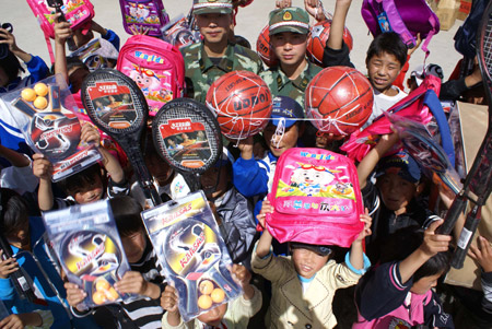 Children show the articles they received at Tibet Children's Welfare Home in Lhasa, capital of southwest China's Tibet Autonomous Region, August 1, 2009. A group of armed policemen paid a visit to Tibet Children's Welfare Home on Saturday and brought children living and learning articles. [Liang Jianming/Xinhua]