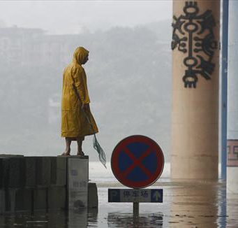 A man stands near a parking lot flooded after a rainstorm in Ciqikou town of Chongqing in southwest China, August 3, 2009. In the next 10 days, the heat weave will continue in most parts of south China while rainstorms will hit the northeast, said Chen Zhenlin, a spokesman for the China Meteorological Administration (CMA). [China Daily]