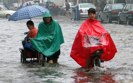 Local Chinese residents paddle in the water on a street after a heavy summer rain hit Jinan, capital city of east China's Shandong Province, August 3, 2009. [Zhao Xiaoming/Xinhua]