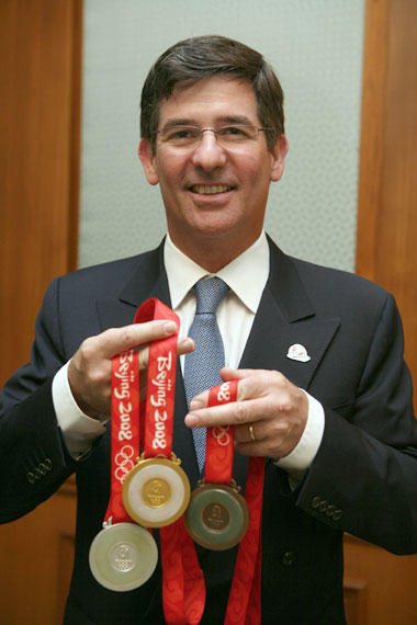 Dines holds the medals that his company provided to the Beijing Olympic Games. He believes the Olympics was a good opportunity to promote the company's value. [Shanghai Daily]