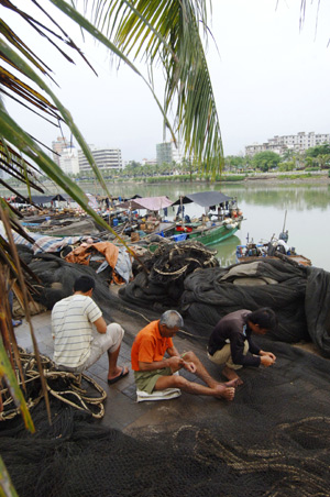 Fishermen repair net at a harbor in Haikou, capital of south China's Hainan Province, Aug. 4, 2009. Tropical storm Goni, formed in the Pacific near Hainan on Monday, is forecast to strike China. [Zhao Yingquan/Xinhua]