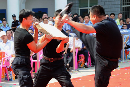 A Chinese policeman breaks a slate of stone with his leg as he shows his skills for the public during a police camp open day in Jingdezhen city in east China's Jiangxi Province, August 4, 2009.[Shi Weiming/Xinhua]