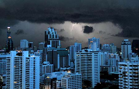 Flashes of lightning illuminate the sky and render the buildings a blue colour in Bangkok on June 13, 2009.[CRI]