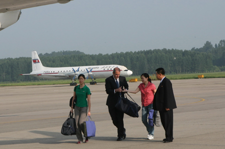 The two female American journalists (1st L and 3rd L) heads to a chartered plane carrying the homebound former U.S. president Bill Clinton at an airport in Pyongyang, capital of the Democratic People's Republic of Korea (DPRK), on Aug. 5, 2009. The two female American journalists just amnestied by the Democratic People's Republic of Korea (DPRK) left Pyongyang on Wednesday morning aboard the chartered plane.[Zhang Binyang/Xinhua]