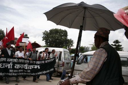 A rickshaw driver looks at the protesters demanding the government to immediately control the spread of diarrhea and immediately declare diarrhea affected regions as health crisis area in Kathmandu, capital of Nepal, Aug. 4, 2009. The epidemic diarrhea, which broke out two months ago, has killed more than 280 people. [Xinhua]