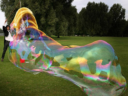 Samsam Bubbleman, a U.S. professional bubble-maker creates what he says the world's largest free-floating soap bubble in a London park. The 'bubbleologist' said his bubble will replace the current Guinness World Record holder, a 9.486-square-meter bubble created in Minnesota in 2005. [chinanews.com.cn] 