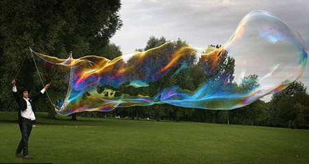 Samsam Bubbleman, a U.S. professional bubble-maker creates what he says the world's largest free-floating soap bubble in a London park. The 'bubbleologist' said his bubble will replace the current Guinness World Record holder, a 9.486-square-meter bubble created in Minnesota in 2005. [chinanews.com.cn]