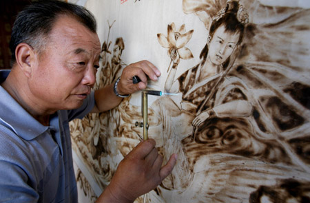 Folk artist Yu Hua paints 'Baxian Guohai', a picture depicting a fairy tale of eight immortals, with a 'fire brush' at home in Yongji City of north China's Shanxi Province, August 4, 2009. Yu Hua has created over 400 pieces of fire-painted artworks, since he created the special way of painting several years ago with a 'fire brush' scorching on the canvas made of white cloth and plank. [Xue Jun/Xinhua]