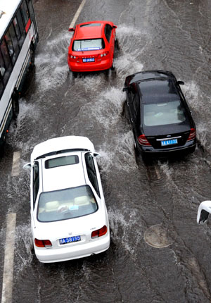 Three cars run on a flooded street in China's Chongqing Municipality, Aug. 4, 2009. Heavy rain hit Chongqing on Tuesday causing traffic jam and the closure of highways. A total of 379,900 people are plagued by the strong rainfalls. [Yang Lei/Xinhua]