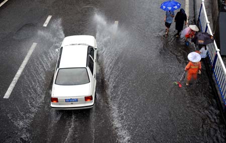 A car runs on a flooded street in China's Chongqing Municipality, Aug. 4, 2009. Heavy rain hit Chongqing on Tuesday causing traffic jam and the closure of highways. A total of 379,900 people are plagued by the strong rainfalls. [Yang Lei/Xinhua]