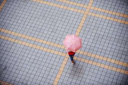 A pedestrian walks in the rain in a street in Guiyang, capital of southwest China's Guizhou Province, Aug. 4, 2009. The rain brought cool breeze to the people in the summer in this city. [Liu Xu/Xinhua]