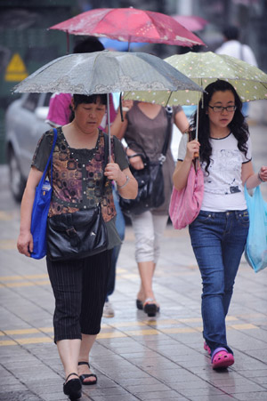 Pedestrians walk in the rain in a street in Guiyang, capital of southwest China's Guizhou Province, Aug. 4, 2009. [Liu Xu/Xinhua]