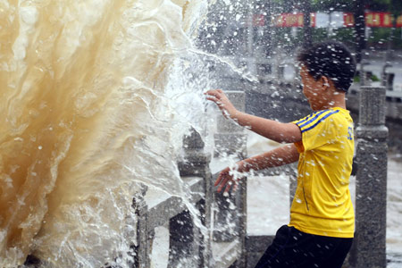 A Chinese boy escapes from an ocean wave splashing on a trestle bridge on the beach near Zhuhai city in south China's Guangdong Province, August 4, 2009 as the tropical storm of 'Goni' approaches to the city. [Li Jianshu/Xinhua]