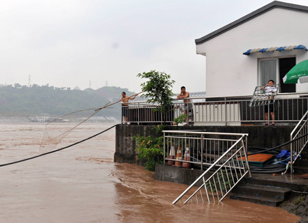 A man nets fish at home as the swollen river reaches the yard in southwest China's Chongqing Municipality, August 4, 2009. The continual heavy rainfalls in Chongqing brought about flood over the city, with many lower sections of the riverside streets submerged. [Zhong Guilin/Xinhua]