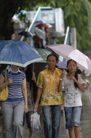 Citizens hold umbrellas in Haikou, capital of south China's Hainan Province, on Aug. 5, 2009. The tropical storm Goni landed at a speed of 83 km per hour early Wednesday morning in Taishan of southern China's Guangdong Province, according to local meteorological station.