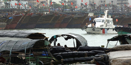 A boat of Xingang Maritime Safety Administration (MSA) patrols at a harbor where many boats and ships take shelter from tropical storms in Haikou, capital of south China's Hainan Province, on Aug. 5, 2009. 