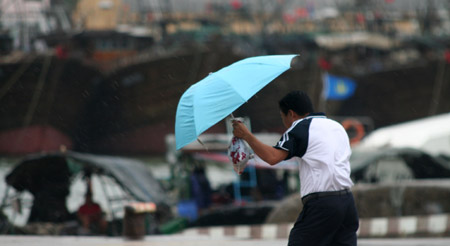 A citizen struggles with his umbrella in Haikou, capital of south China's Hainan Province, on Aug. 5, 2009. The tropical storm Goni landed at a speed of 83 km per hour early Wednesday morning in Taishan of southern China's Guangdong Province, according to local meteorological station.