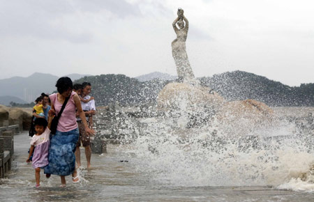 Chinese tourists escape from the ocean waves splashing on a trestle bridge on the beach near Zhuhai city in south China's Guangdong Province, August 4, 2009 as the tropical storm of 'Goni' approaches to the city. [Li Jianshu/Xinhua]