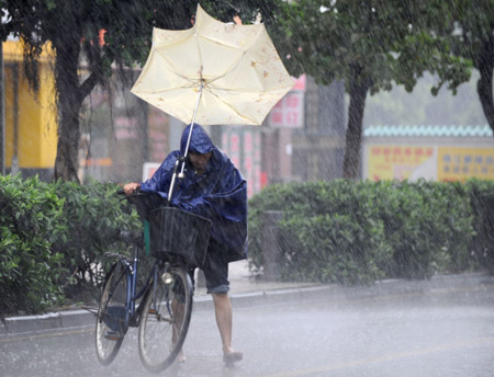 A local struggles in the rain in Guangzhou, capital of south China's Guangdong Province, on Aug. 5, 2009. The tropical storm Goni landed at a speed of 83 km per hour early Wednesday morning in Taishan of Guangdong Province, according to local meteorological station.