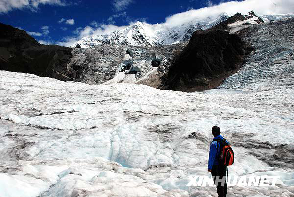 A tourist enjoys the Midui glacier of Tibet on July 31, 2009. Located in Yupu Town, Bomi County, the summit of the glacier is 6,800 meters above sea level and extends about 20 kilometers. The snow line of the glacier mountain is 4,600 meters above sea level. In 2007, local residents opened a Midui glacier travel spot. [Photo: Xinhuanet]